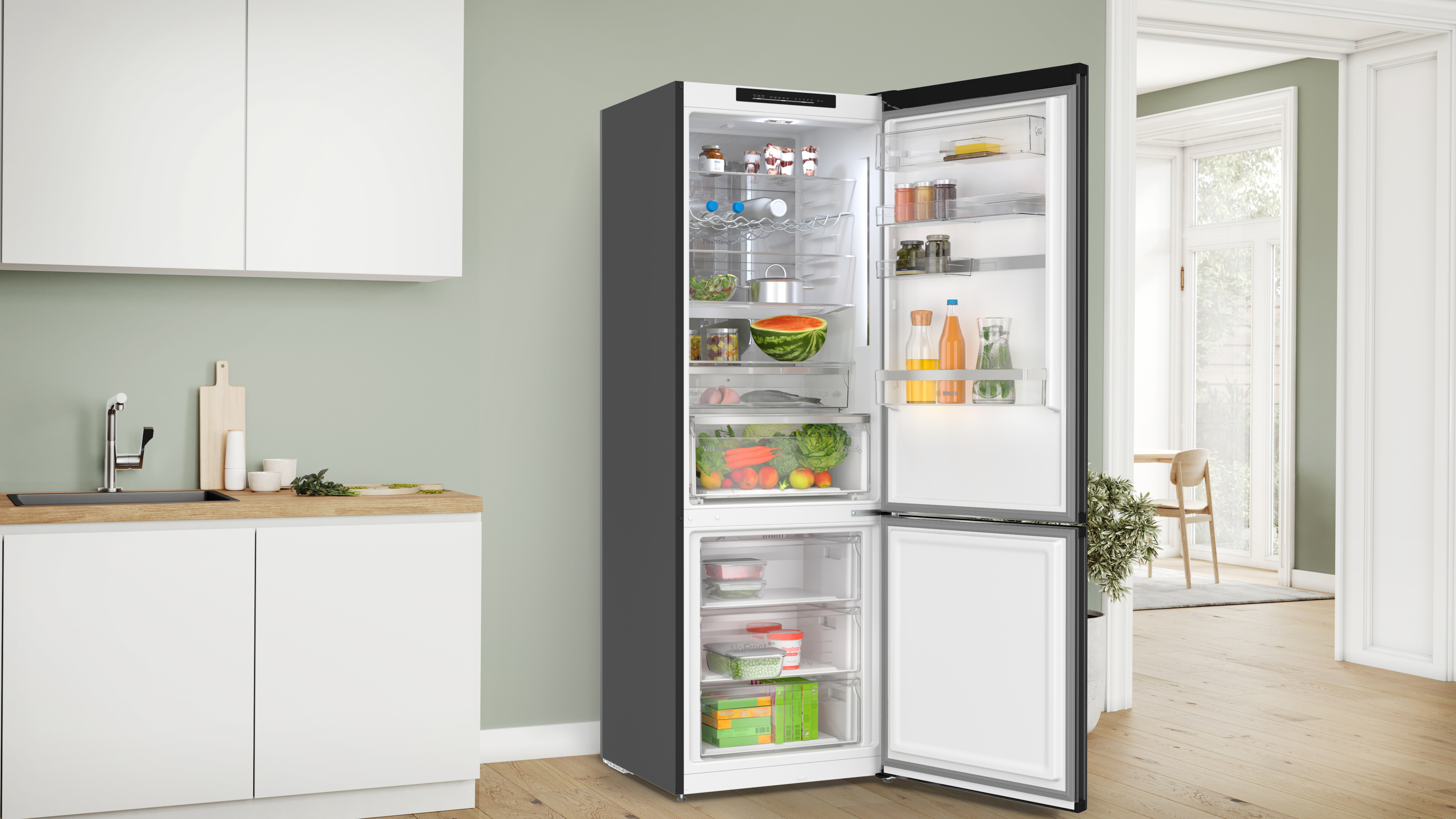 Open modern refrigerator with fresh groceries visible shelves of jars bottles vegetables and a watermelon on the lower shelf in a bright minimal kitchen Globalmtc