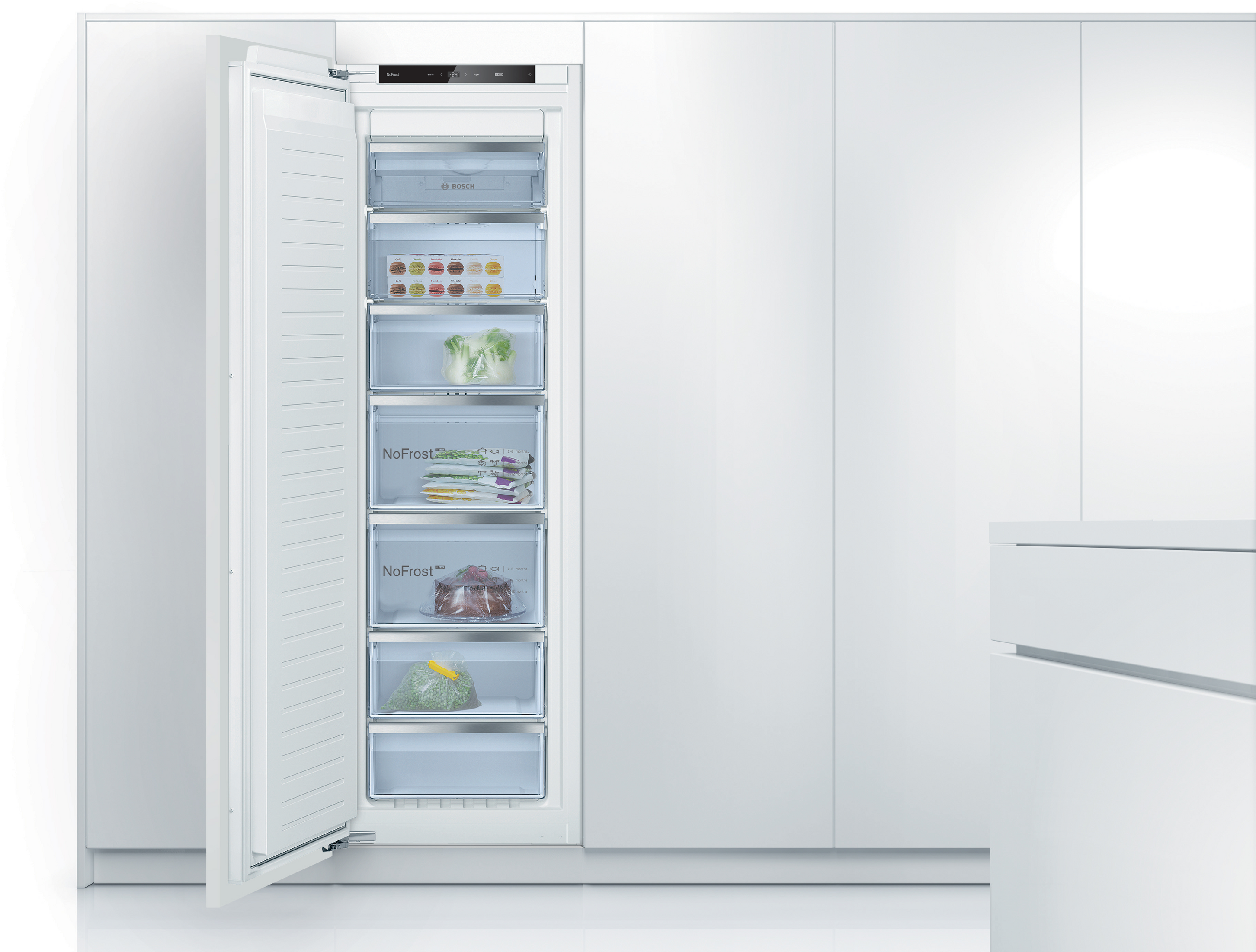 Open bosch nofrost freezer built into white cabinetry with multiple transparent drawers showing frozen vegetables and packaged items Globalmtc